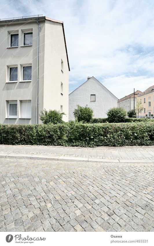 Siedlung Stadt Wohngebiet Straße Kopfsteinpflaster Haus Wohnhaus Wohnsiedlung Gedeckte Farben Hecke Sommer grün grau weiß blau Himmel Wolken bedeckt Sonnenlicht