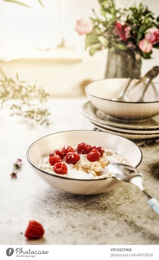 Frühstücksbrei Schüssel mit Himbeeren auf dem Tisch am Fenster Hintergrund Haferbrei Schalen & Schüsseln Lebensmittel selbstgemacht Gesundheit Müsli Löffel