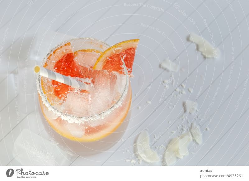 Vitaminwasser mit Grapefruit, Kokosnussraspeln am Glasrand und Eiswürfel mit Trinkhalm Getränk Erfrischungsgetränk Limonade orange weiß Kokosraspeln Diät