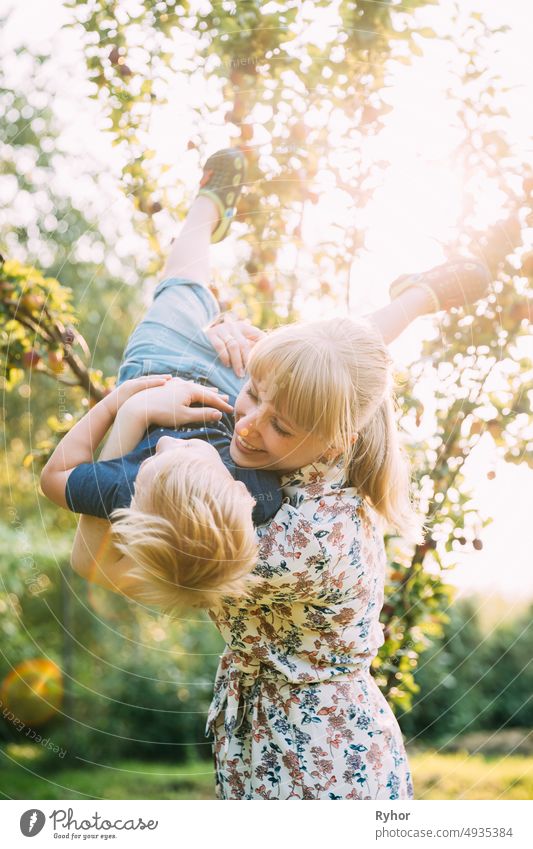 Junge Frau Mutter umarmt ihr Baby Sohn im sonnigen Garten. Outdoor Sommer Porträt schön blond Pflege Kaukasier Kind Kindheit filigran Kleid Abend Familie Spaß