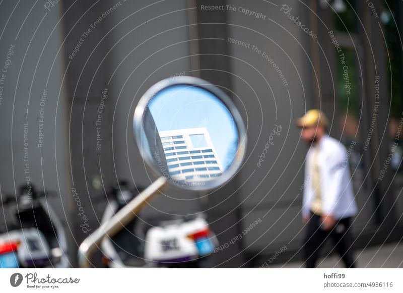 ein Ausschnitt eines Hochhauses mit blauem Himmel im Spiegel eines Motorrollers Aussenspiegel rückblickend Spiegelbild Rückspiegel Rückblick Fassade Motorrad