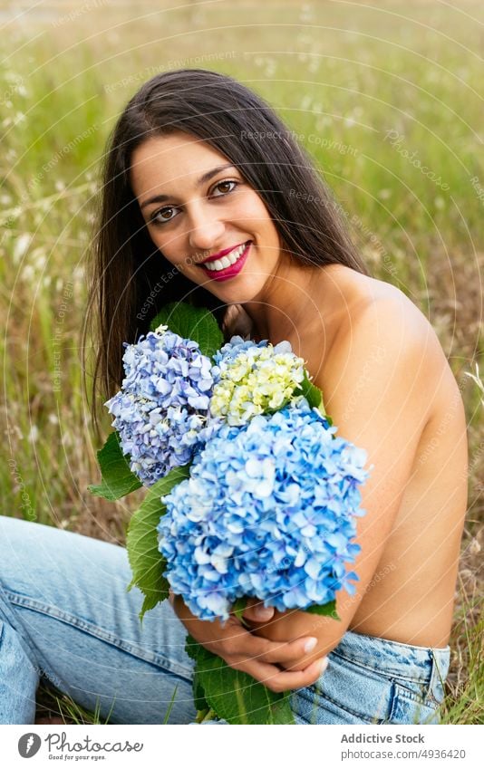 Glückliche, verführerische Dame mit einem Strauß zarter Hortensienblüten im Park Frau Blume Lächeln oben ohne Wiese Deckbrust feminin positiv sanft Feld Natur