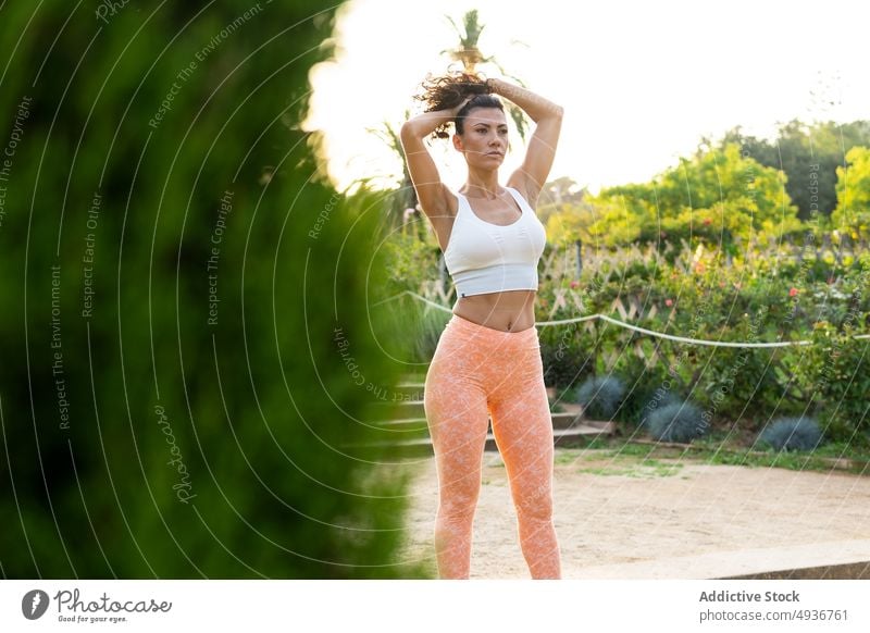 Schlanke Frau macht Pferdeschwanz im Park Sportlerin Training Frisur Fitness Gesunder Lebensstil Vorschein sportlich Stil Form passen Pflanze Sportbekleidung