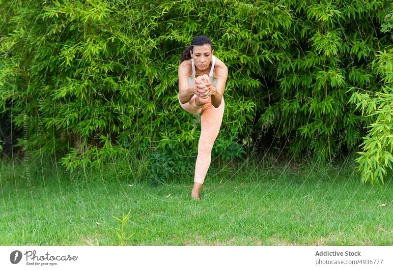 Frau macht Stehende Hand zum großen Zeh Asana im Park Training stehende Hand bis zum großen Zeh Yoga Übung üben Gleichgewicht Rasen Zen Sportbekleidung Hobby