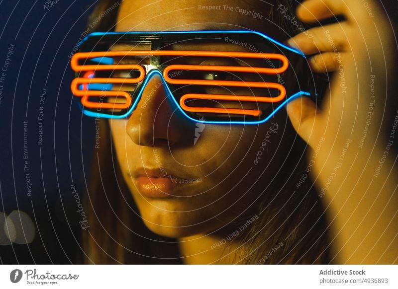 Junge Frau mit futuristischer Brille bei Nacht dunkel Stil Vorschein neonfarbig Porträt Cyberpunk dunkles Haar jung Persönlichkeit Menschliches Gesicht