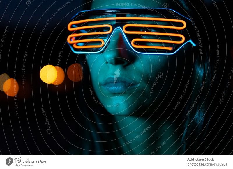 Junge Frau mit futuristischer Brille bei Nacht dunkel Stil Vorschein neonfarbig Porträt Cyberpunk dunkles Haar jung Persönlichkeit Menschliches Gesicht