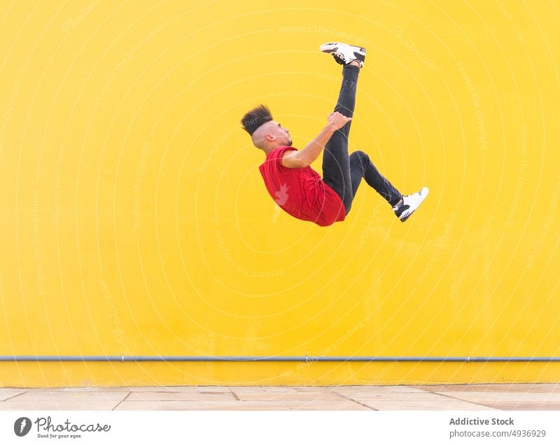 Mann macht Parkour-Trick in der Nähe der gelben Wand Le Parkour Überschlag Stunt springen extrem Großstadt Gebäude Straße männlich urban Energie Flip Freiheit