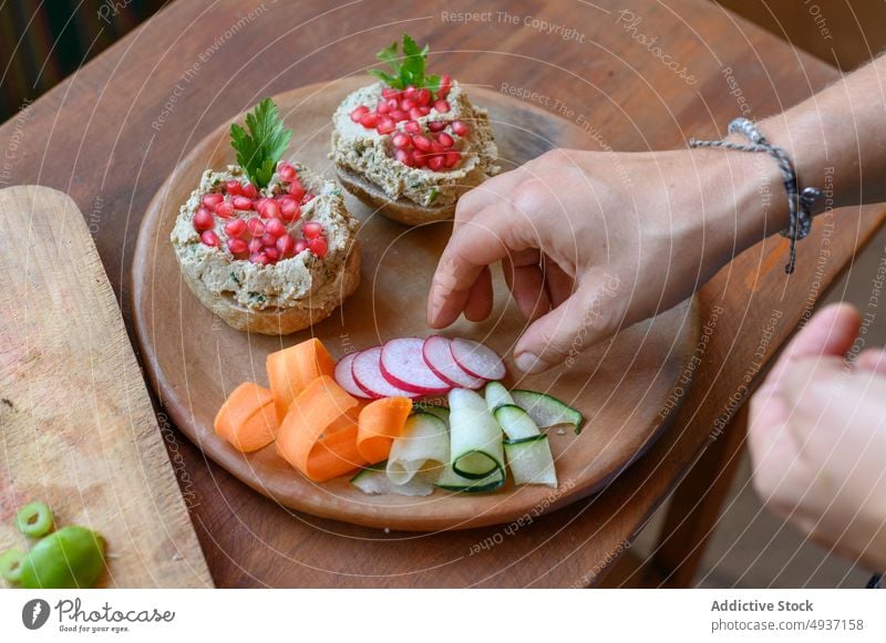 Erntehelfer serviert vegetarisches Essen auf Holzteller Person Vegetarier Lebensmittel Gemüse dienen Teller Belegtes Brot pate Speise Veganer Granatapfel Samen