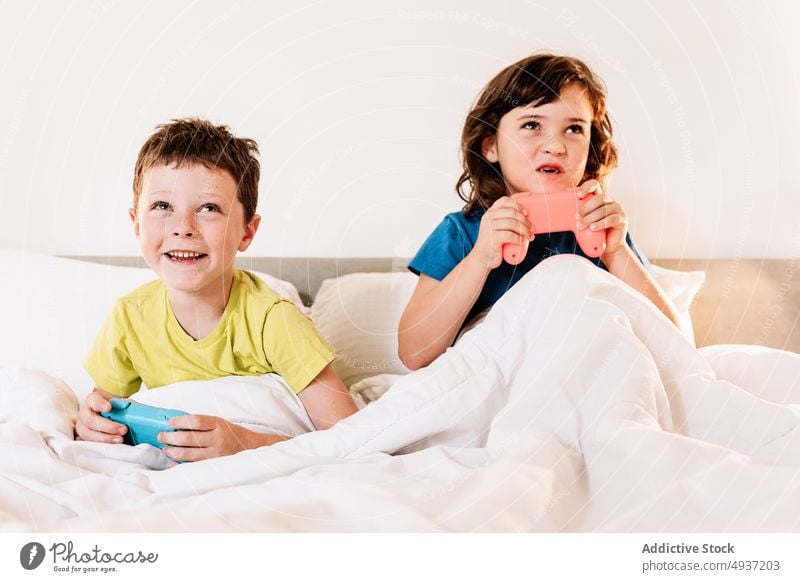 Kinder spielen ein Videospiel im Bett Geschwisterkind Gamepad unterhalten Vergnügen Zeitvertreib Freizeit Hobby fokussiert Schwester konzentriert Bruder Junge