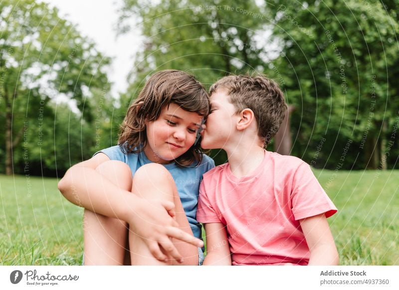 Bruder verrät Geheimnis an Schwester im Park Geschwisterkind Kinder geheim hauchen Sommer Wochenende Gerücht Zusammensein Freund ruhen Junge Mädchen Ohr