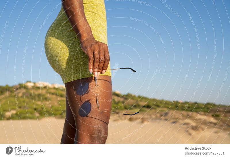 Crop African American weiblich gegen blauen Himmel am Strand Frau Tourist Sommer Stil Blauer Himmel Hügel Sonnenbrille Kleid Wochenende schwarz Afroamerikaner