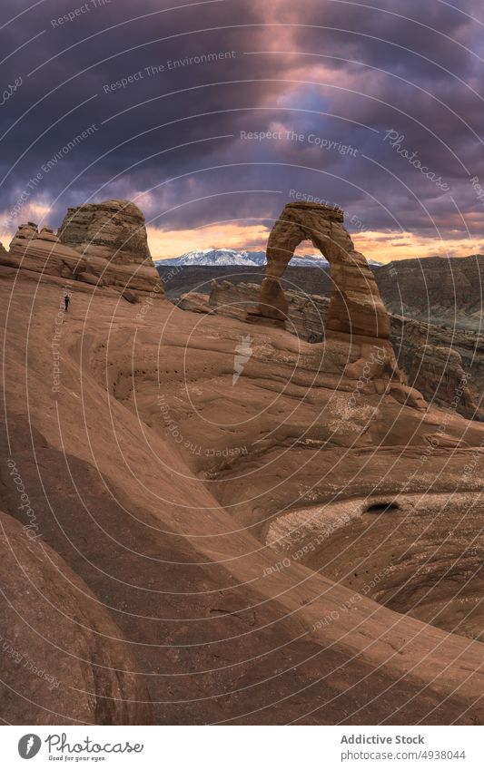 Reisende in der Nähe von Steinbogen gegen Sonnenuntergang Himmel Reisender Bogen Formation wüst wolkig Natur trocken Entdecker Arches National Park bewundern