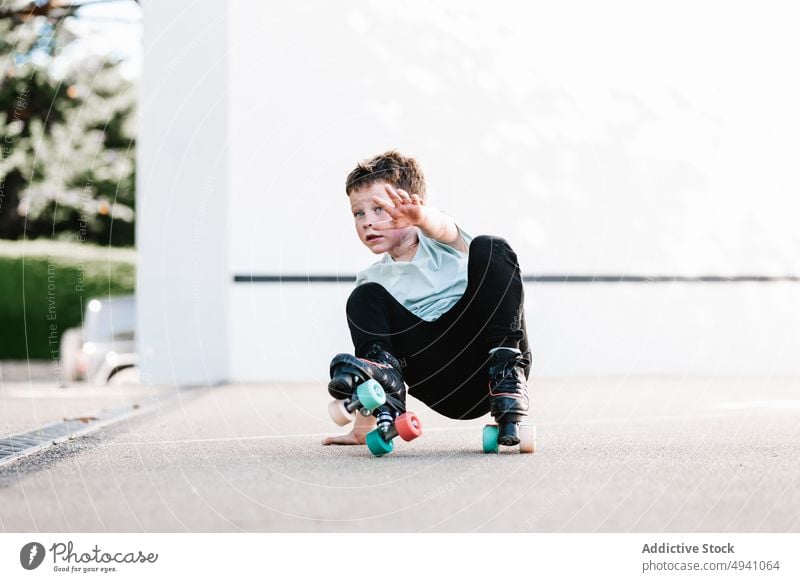 Junge in Rollschuhen auf den Hüften sitzend Voute Rollerskate Straße Sommer Wochenende urban Kindheit Pause Erholung Aktivität tagsüber sonnenbeschienen lässig