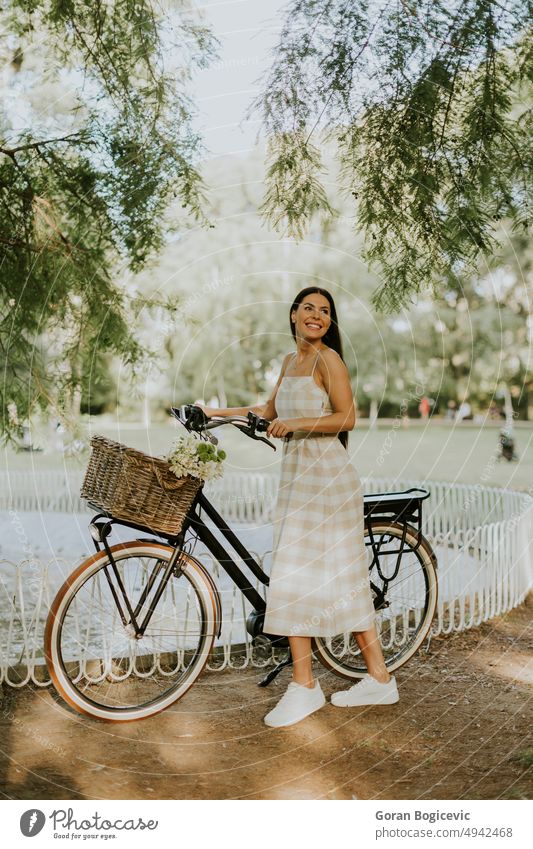 Junge Frau mit Blumen im Korb eines Elektrofahrrads aktiv Aktivität Erwachsener schön Fahrrad Kaukasier Fahrradfahren Tag ebike Übung Blumenkorb Freizeit