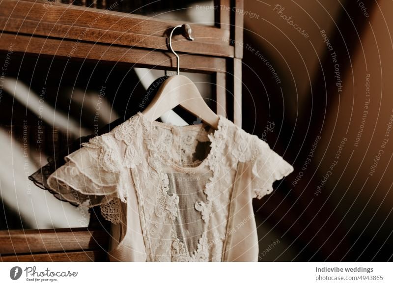 Ein schönes Detail eines Hochzeitskleides, das an einem alten Holzschrank mit Glas hängt. Hochzeit Vorbereitung Bild, mit weiß-beige Spitze Kleid auf einem Vintage-Holz-Bügel.