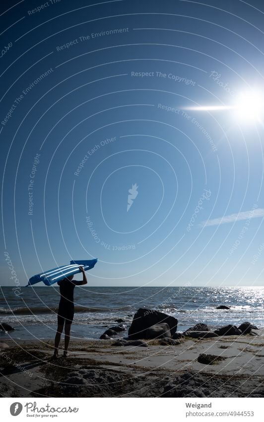 Kind mit blauer Luftmatratze am Ostsee-Strand bei Sonnenschein Sommer Felsen Urlaub Ferien Gegenlicht Nordsee Norddeutschland Schleswig-Holstein Erholung Spaß