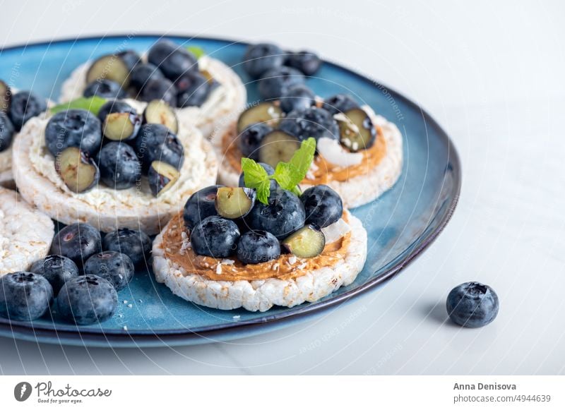 Gesunde offene Sandwiches mit Blaubeeren Reiscrisps Belegtes Brot Erdnussbutter Nussbutter gesunder Snack Reiswaffeln Cracker Gesundheit Mandel Cashewnuss Minze