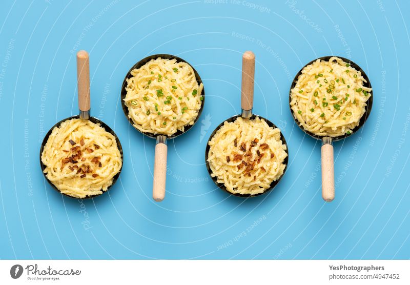 Spätzle in Eisenpfannen auf einem blauen Tisch. Deutsche Nudeln mit gerösteten Zwiebeln und Schnittlauch oben Österreicher Hintergrund gebacken bayerisch