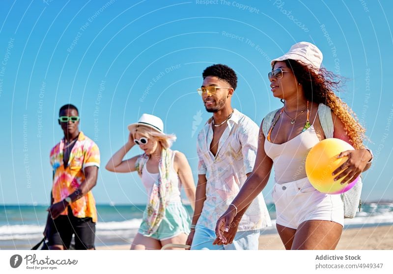 Glückliche Freunde am Strand Spaziergang Lächeln Sommer Wochenende Zusammensein Sand Blauer Himmel Resort tagsüber Männer froh Frauen jung Freude schlendern