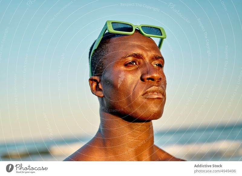 Ernster schwarzer Mann am Meer bei Sonnenuntergang MEER Strand Urlaub ernst Wochenende Wolkenloser Himmel Sonnenbrille Porträt männlich Afroamerikaner ethnisch