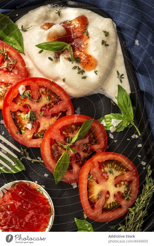 Leckeres Gericht mit Tomaten, Käse und Kräutern auf dem Tablett Burrata Saucen Basilikum Thymian Mozzarella lecker Gemüse Kraut appetitlich Stoff Salz Produkt