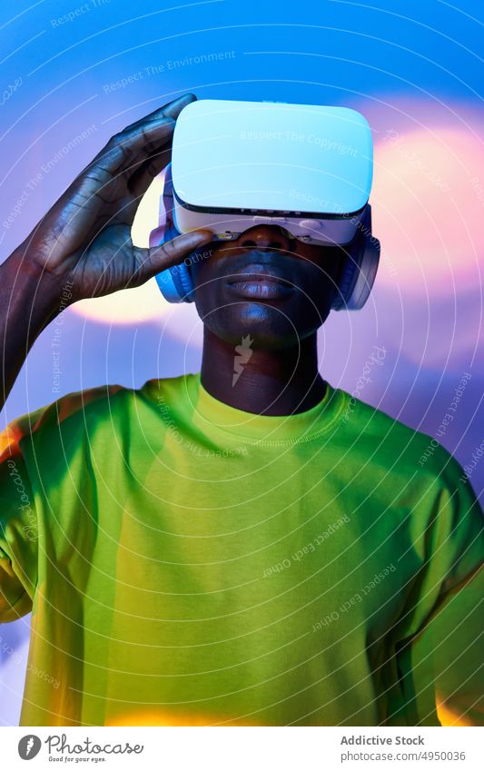 Junger afroamerikanischer Mann sieht Video in VR-Brille Virtuelle Realität zuschauen Konzentration eintauchen Erfahrung erkunden futuristisch Cyberspace