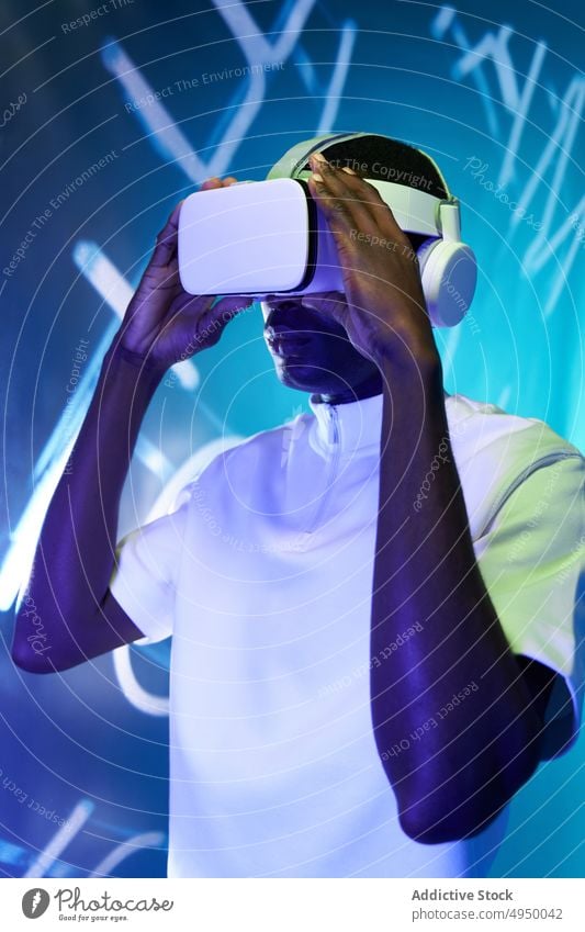 Junger afroamerikanischer Mann sieht Video in VR-Brille Virtuelle Realität zuschauen Konzentration eintauchen Erfahrung erkunden futuristisch Cyberspace