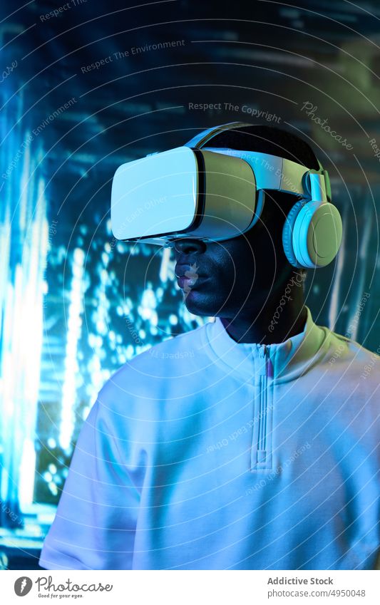 Junger afroamerikanischer Mann sieht Video in VR-Brille Virtuelle Realität zuschauen Konzentration eintauchen Erfahrung erkunden futuristisch Cyberspace