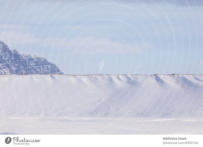 Straße in der Nähe eines verschneiten Berges im Winter Hügel Schnee Berge u. Gebirge wolkig Himmel gerade kalt Natur Island atemberaubend Landschaft Kamm