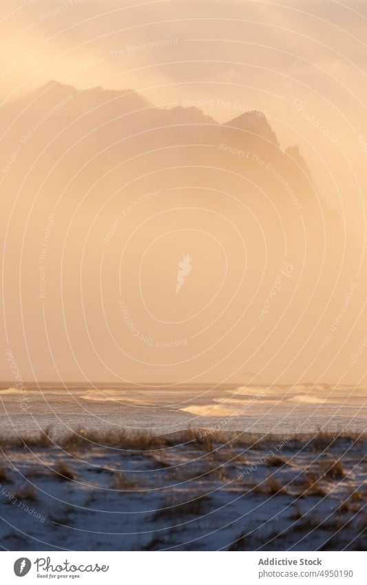 Verschneite Ebene in der Nähe von Bergen bei Sonnenuntergang Tal Gras Schnee Berge u. Gebirge kalt Nebel vage Landschaft Winter Island Kamm Wetter Natur