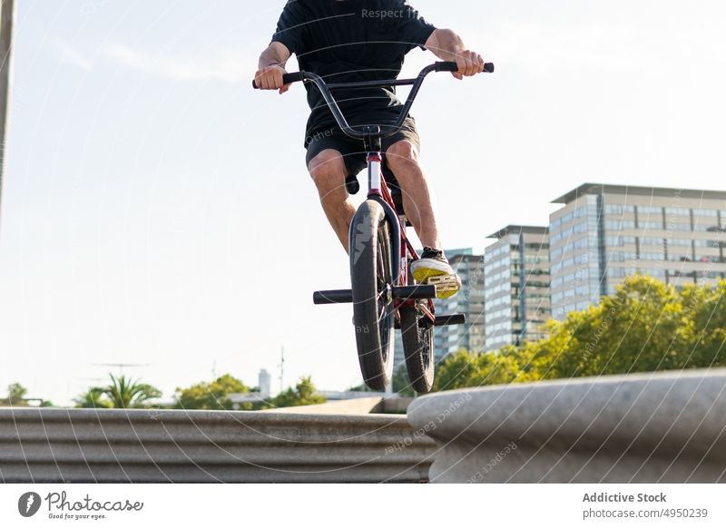 Anonymer junger Mann auf dem Fahrrad an der Grenze Mitfahrgelegenheit Borte Gleichgewicht Straße bmx Trick Saum Sommer männlich lässig sonnig tagsüber Radfahrer