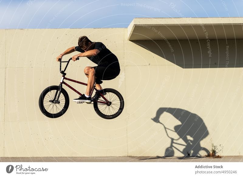 Mann macht Sprungtrick auf BMX-Rad springen Fahrrad bmx Trick Wand Straße Wochenende Sommer Aktivität männlich Energie urban Stunt lässig Radfahrer Zeitgenosse