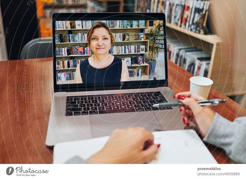 Studentin beim Lernen in der Universitätsbibliothek. Junge Frau, die einen Videokurs besucht und sich einen Online-Kurs anhört, indem sie einen Laptop benutzt. Konzentrierte Studentin beim Lernen für College-Prüfungen. Technologie nutzen