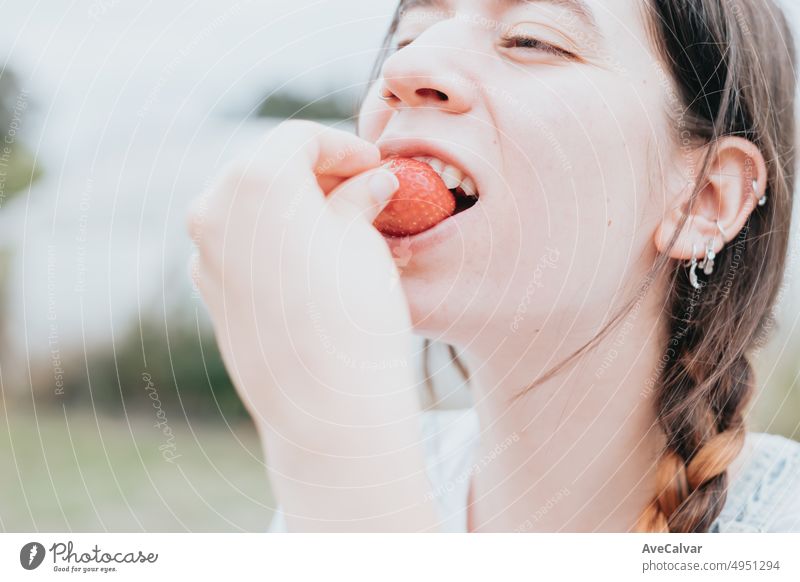 Positive Frau Landarbeiter Verkostung geerntet Erdbeere, arbeiten im Gewächshaus. Gesunde Lebensweise und gesunde Ernährung.Obst und Beeren Bäuerin mit Erdbeerernte. Lächelnde Frau hält Strohhalme