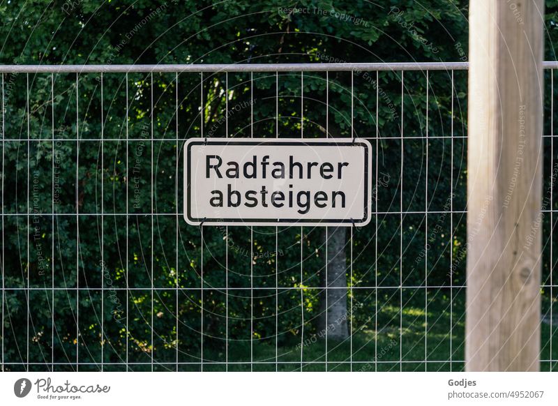 Radfahrer absteigen - Schild an einem Bauzaun radfahrer Schilder & Markierungen Aufforderung gebüsch Außenaufnahme Hinweisschild Barriere Menschenleer Baustelle