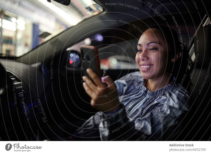 Frau benutzt Smartphone im Auto PKW Passagier benutzend Browsen Großstadt Nacht Automobil dunkel Mobile Telefon Funktelefon Surfen Internet Nachricht urban