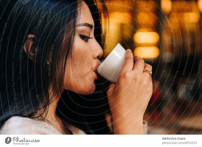 Crop Asiatische Frau genießt Kaffee in Cafeteria trinken lecker Aroma Getränk Heißgetränk Tasse genießen Kaffeehaus feminin Kantine natürlich Café idyllisch