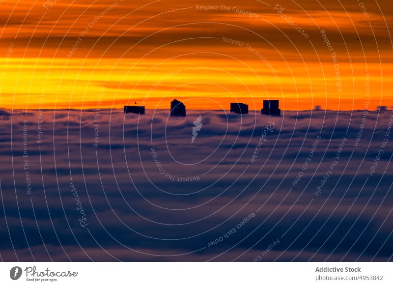 Silhouette von modernen Gebäuden zwischen Wolken bei Sonnenaufgang Sonnenuntergang Himmel hoch Natur aktiv extrem Nebel Klippe Top Gipfel männlich