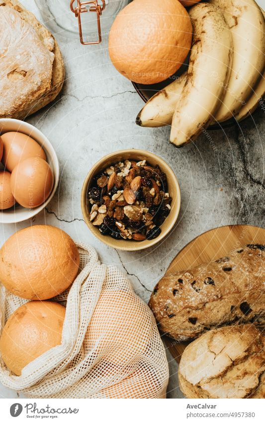 Draufsicht auf ein gesundes Frühstück mit verschiedenen Nüssen, Walnüssen, Rosinen und Mandeln, kombiniert mit Bananen, Orangen, Eiern und Brot, um Toasts mit Omelett zu machen. Energieversorgung, Vitamine und Proteine für die Ernährung