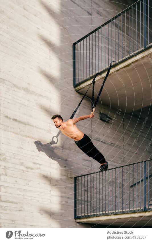 Sportlicher Mann balanciert auf Gymnastikringen Sportler Ausgewogenheit gymnastisch Ring ohne Hemd Großstadt sportlich jung aktiv Training Konstruktion Körper