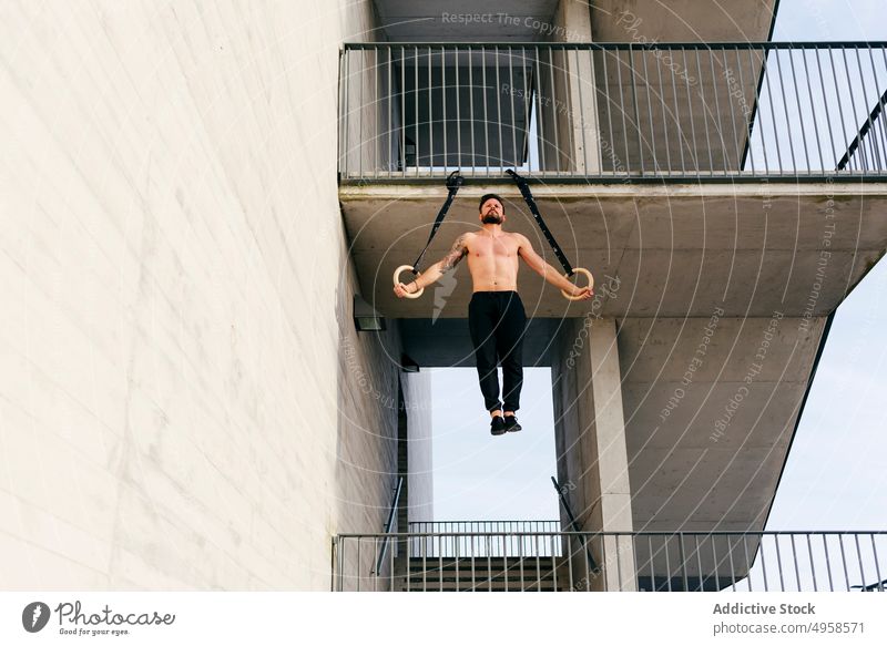 Sportlicher Mann balanciert auf Gymnastikringen Sportler Ausgewogenheit gymnastisch Ring ohne Hemd Großstadt sportlich jung aktiv Training Konstruktion Körper