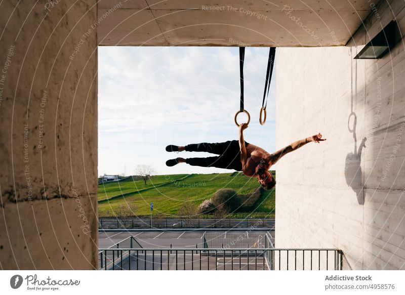 Sportlicher Mann balanciert auf Gymnastikringen Sportler Ausgewogenheit gymnastisch Ring ohne Hemd Großstadt sportlich jung aktiv Training Konstruktion Körper