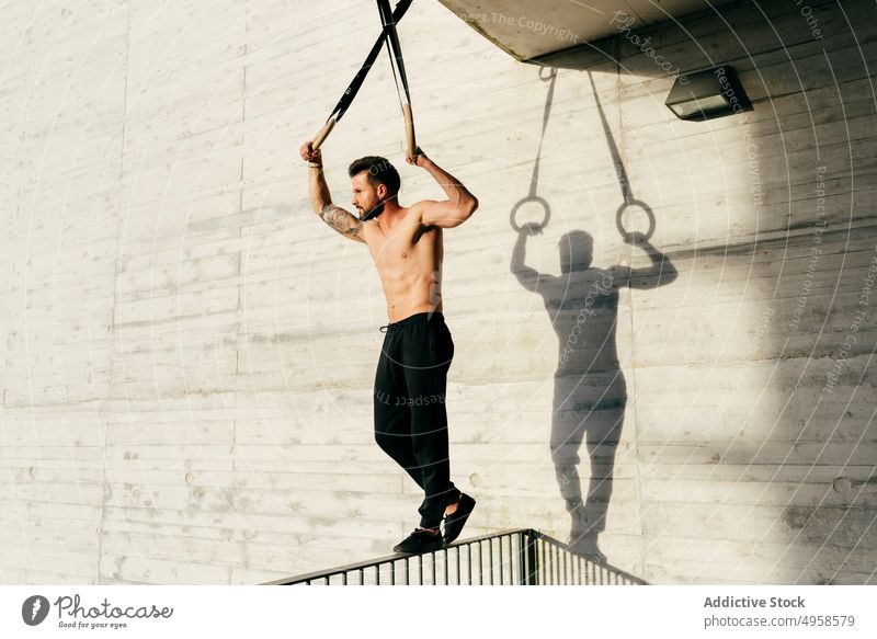 Sportlicher Mann balanciert auf Gymnastikringen Sportler Ausgewogenheit gymnastisch Ring ohne Hemd Großstadt sportlich jung aktiv Training Konstruktion Körper