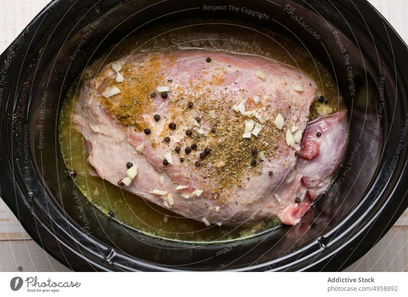 Köstlich gewürztes Fleisch in Marinade mit Gewürzen im Slow Cooker Schongarer lecker roh Lebensmittel Mahlzeit geschmackvoll Bohnenkraut Kochtopf Küche Rezept