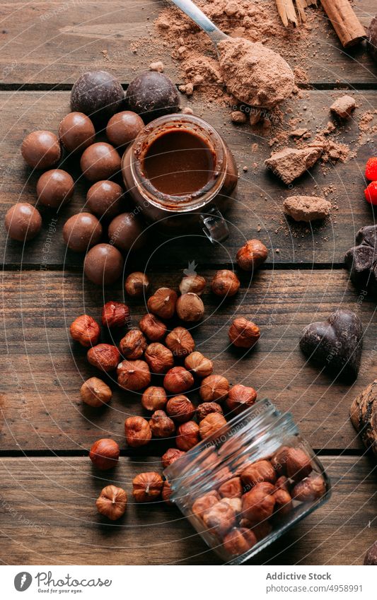 Leckere verschiedene Schokoladenbonbons und Nüsse auf einem Tisch mit Zutaten süß Dessert handgefertigt Erdnuss Butter Zimt Walnussholz Haselnuss lecker