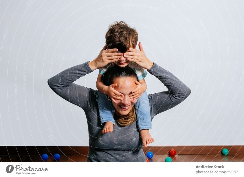 Glückliche Frau trägt ihren Sohn auf den Schultern Mutter spielen heimwärts Spaß Ebene so tun, als ob führen aufgeregt Zusammensein Junge Kind Kleinkind Fliege