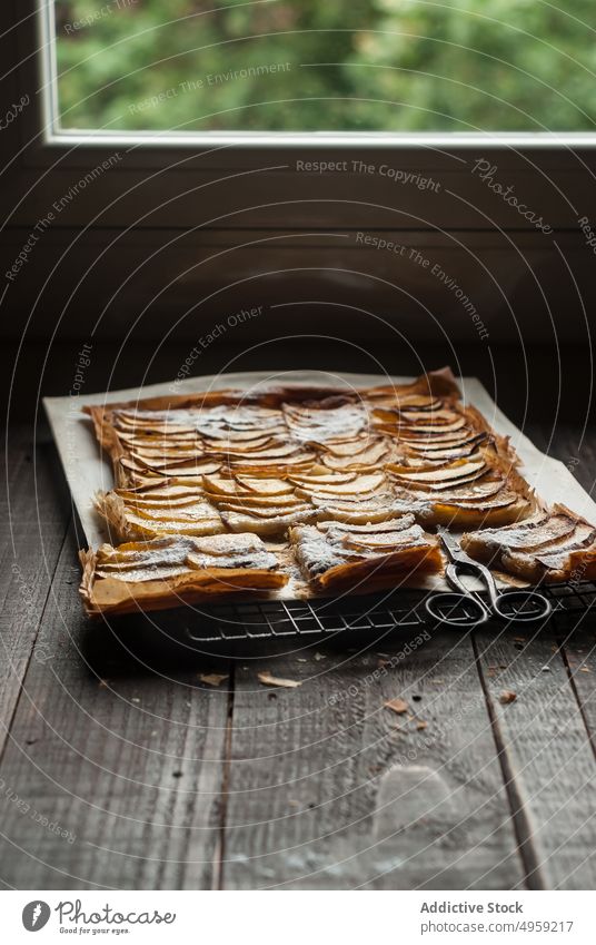 Apfelkuchen in Stücken auf Pergamentpapier serviert Pasteten frisch Holz rustikal Fenster Frangipane selbstgemacht Tageslicht braun Konditorei organisch warm