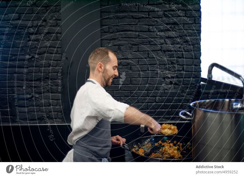 Küchenhilfe rührt in einer Pfanne Küchenchef Mann mitreißend Essen zubereiten Restaurant Lebensmittel kulinarisch männlich professionell Mahlzeit Beruf