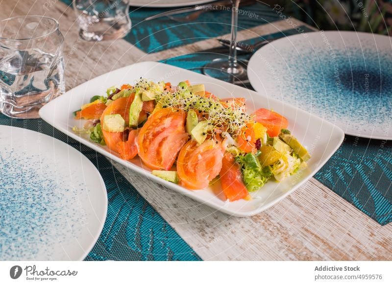 Teller mit leckerem Tomatensalat im Restaurant Salatbeilage gesunde Ernährung Mahlzeit Mittagessen Abendessen Speisekarte geschmackvoll Vitamin mischen Glas