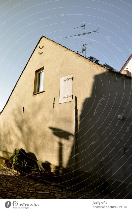 Haus am Berg Schatten Straßenlampe Straßenlaterne Weg Kopfsteinpflaster Giebelseite Fenster Antenne Licht Fassade Gebäude Wand Himmel wohnen Einfamilienhaus